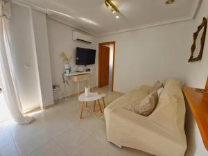 uma sala de estar com um sofá e uma televisão em ATICO CON BARBACOA em Torrevieja