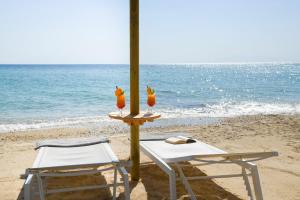 2 sillas y una mesa en la playa en Potidea Palace Hotel en Nea Potidaea