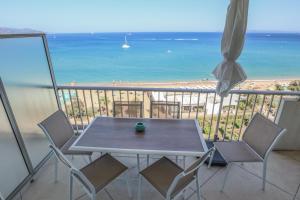 une table et des chaises sur un balcon avec la plage dans l'établissement Bord de plage - Studio en front de mer, au Lavandou