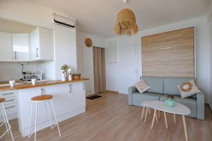 Il dispose d'une cuisine et d'un salon avec un canapé et une table. dans l'établissement Bord de plage - Studio en front de mer, au Lavandou
