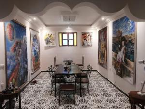 a dining room with a table and many paintings on the walls at Apartment Ghazoua in Essaouira
