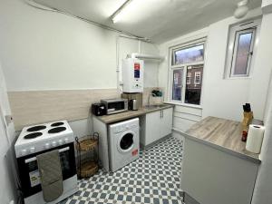 a small kitchen with a stove and a washing machine at Spectacular 2 bedroom on Tower Bridge in London