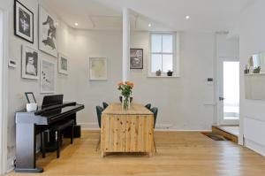 uma sala com um piano e uma mesa com flores em Beautiful Battersea Home by Clapham Junction by UnderTheDoormat em Londres