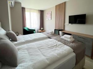 a hotel room with a large bed and a television at Хотел BLISS in Kazichene