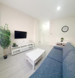 uma sala de estar com um sofá azul e uma televisão em Apartamento Plaza Calzada 3 em Sanlúcar de Barrameda
