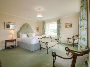 a bedroom with a bed and two chairs and a window at Glamis House in Forfar