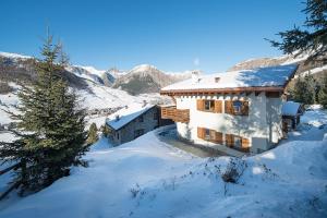 una casa nella neve con montagne sullo sfondo di Chalet Elena a Livigno