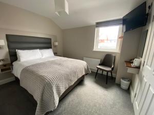 a bedroom with a bed and a chair and a window at Murphy's Pub and Bed & Breakfast in Dingle