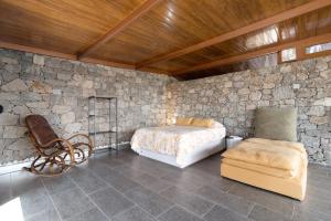 a bedroom with a bed and a chair in a stone wall at La Casita de la Orilla de Peñate in Santa Brígida