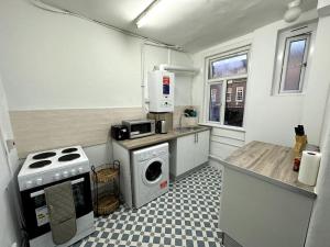 a small kitchen with a stove and a washing machine at Magnificent 2 Bedroom On Tower Bridge in London