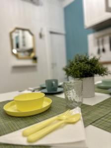 a table with a yellow plate and a yellow fork and knife at Aquarium Exclusive Loft - Free Parking in Genoa