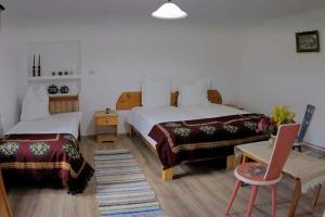 1 dormitorio con 2 camas, mesa y silla en Andrada's House Soars, en Şoarş