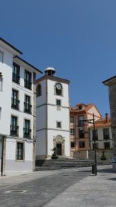 a building with a clock tower in front of a building at Apartamentos El Reloj in Luanco