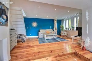 a living room with a couch and a blue wall at La Carlina - Loft entre lac et montagnes in Orcier