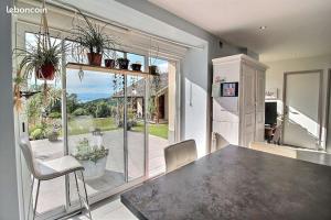 a kitchen with a table and chairs and a large window at La Carlina - logements entre lac et montagnes in Orcier