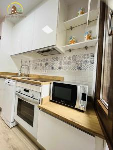 une cuisine avec des placards blancs et un four micro-ondes sur un comptoir dans l'établissement Casa de la Galera Alojamiento Turístico en Toledo, à Tolède