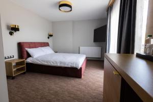 WiżajnyにあるAgroturystyka Kalinkaのベッドとデスクが備わるホテルルームです。