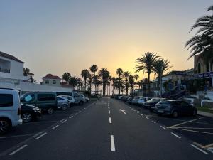 an empty parking lot with parked cars and palm trees at Surf Station Tenerife Holiday Apartment Las Americas in Playa de las Americas