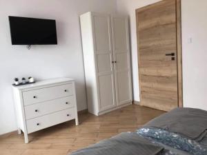 1 dormitorio con 1 cama y vestidor con TV en Willa Luna, en Jarosławiec