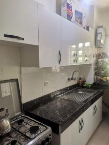 uma cozinha com armários brancos, um lavatório e um fogão em Un appartement à proximité de la corniche Hoceima pour les familles em Al Hoceïma
