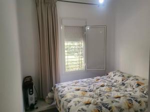 1 dormitorio con 1 cama frente a una ventana en Un appartement à proximité de la corniche Hoceima pour les familles, en Alhucemas
