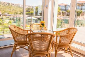 a glass table with three chairs and a table with a vase of flowers at Villa Viktor in Topola