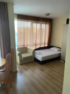 a bedroom with a bed and a chair and a window at Viva Apartment in Sunny Beach