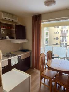 a kitchen and dining room with a table and a balcony at Viva Apartment in Sunny Beach
