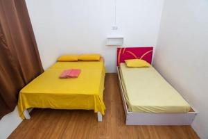 two beds in a room with yellow and pink sheets at Ohana Guest House in Crève Coeur