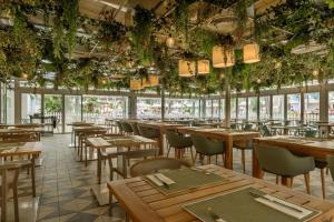 un restaurant avec des tables, des chaises et des plantes au plafond dans l'établissement FERGUS Club Palmanova Park, à Palma Nova