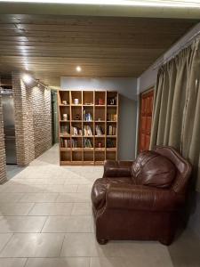 a living room with a leather couch and a book shelf at Magic View 4U Luxury Villa, Tago Vibes in Kineta