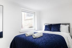 a bedroom with a blue bed with two pillows on it at Chic Urban 2 Bedroom Apartments in Cardiff