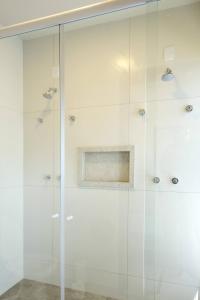 um chuveiro com portas de vidro na casa de banho em Vila Poção em Brotas