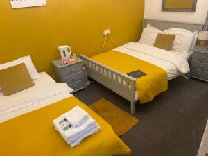 two beds in a room with yellow walls at Bradburys of Blackpool in Blackpool