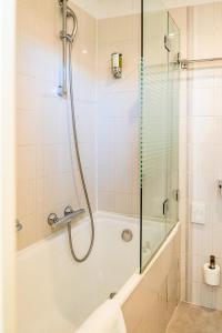 La salle de bains est pourvue d'une douche et d'une baignoire avec une porte en verre. dans l'établissement Hôtel Du Golfe, à Ajaccio
