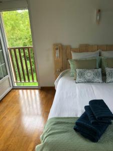 una camera da letto con un grande letto con asciugamani di Grande Chambre Familiale VERTE Tout Bonnement Bien a Putot-en-Auge