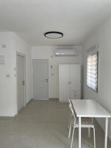 a white room with a white table and chairs at במורד ההר in Shelomi