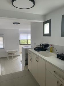 a white kitchen with a sink and a counter top at במורד ההר in Shelomi