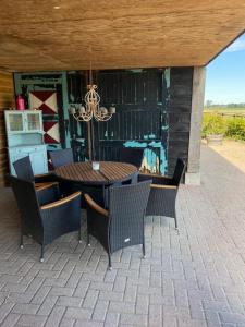 een patio met een tafel en stoelen en een kroonluchter bij Polderzicht in Castricum