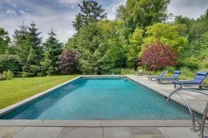 a swimming pool in a yard with two blue chairs at Stockbridge Retreat with Pool and Hot Tub! in Stockbridge