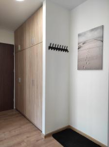 a room with a white wall and a wooden cabinet at Apartament Mazury in Kętrzyn