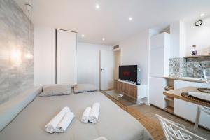 a living room with white furniture and a tv at Cannes Centre - 10mn Palais, Plages, Croisette - AT in Cannes