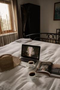 a laptop computer sitting on a bed with two cups of coffee at Vila Lio & Restaurant Devojacki Bunar in Novi Vladimirovac