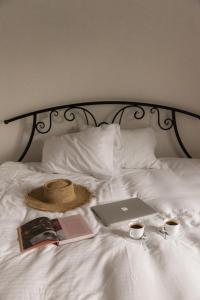 a hat and a laptop on a bed with two cups of coffee at Vila Lio & Restaurant Devojacki Bunar in Novi Vladimirovac