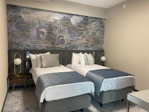 ein Schlafzimmer mit 2 Betten und einem Wandgemälde in der Unterkunft Tisia Hotel & Spa in Tiszaújváros