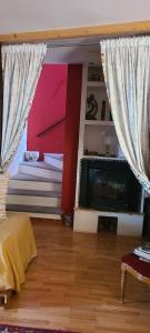 sypialnia z łóżkiem, telewizorem i zasłonami w obiekcie B&B Ma Maison w mieście Govone