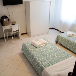 um quarto com 2 camas, uma mesa e uma secretária em Guest House Malaguzzi em Reggio Emilia