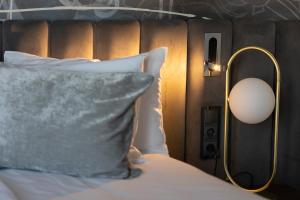 łóżko z białą poduszką i lampą w obiekcie Tisia Hotel & Spa w Tiszaújváros