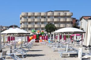 Hotel Graziella في ريميني: مجموعة من الكراسي والمظلات على الشاطئ