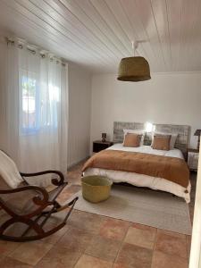 a bedroom with a large bed and a chair at Le vieux poirier à la Plaine des Cafres in Le Tampon